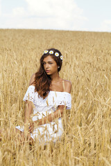 Wall Mural - Young woman in a wheat golden field