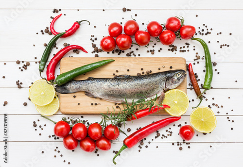 Fototapeta do kuchni Trout fish on wooden cutting board with cherry tomatoes