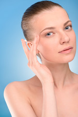 Sticker - Woman applying lifting cream on face, over blue background. 