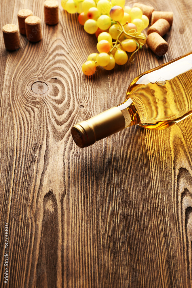 Glass bottle of wine with corks on wooden table background