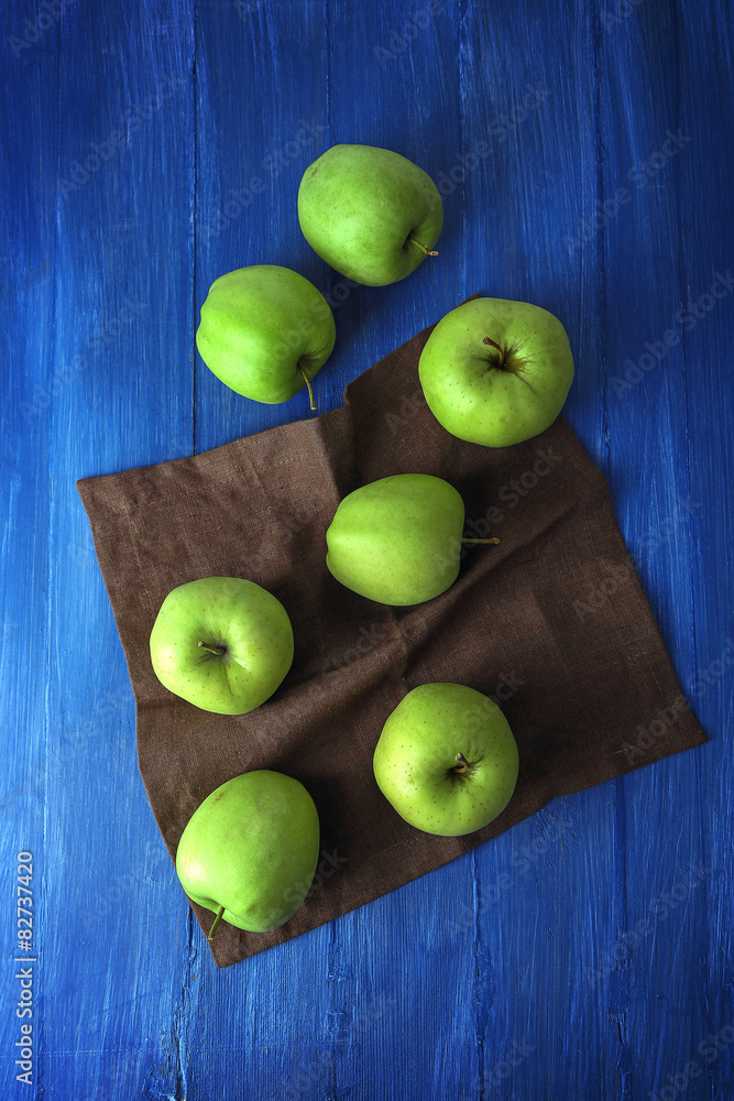 Green apples on wooden table with napkin, top view