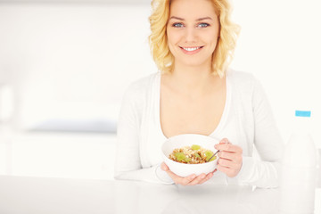 Poster - Young woman eating cereal in the kitchen