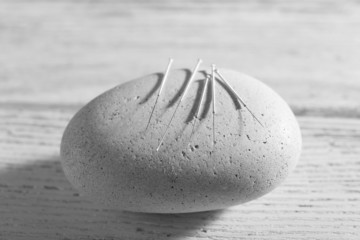 Poster - Acupuncture needles on spa stone on wooden table, closeup