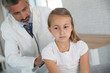 © goodluz - Doctor examining young girl with stethoscope
