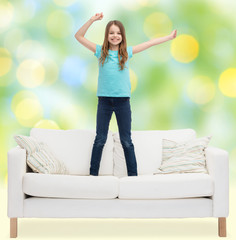 Canvas Print - smiling little girl jumping on sofa