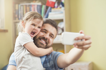 Young father with his cute little daughter taking selfie