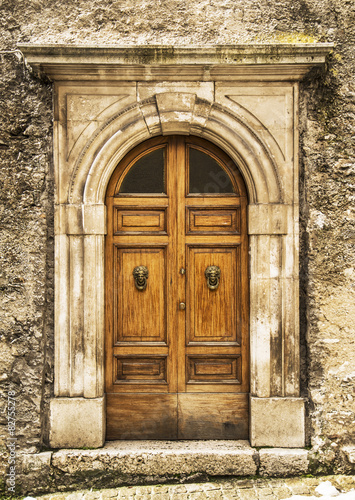 stare-drewniane-wloskie-drzwi-z-licznymi-zdobieniami-na-kamiennej-powierzchni