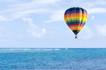 Wall Mural - Hot air balloon over ocean and clouds blue sky