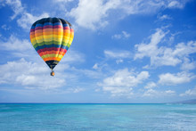 Hot Air Balloon Over Ocean And Clouds Blue Sky