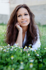 Wall Mural - Brunette cool girl with brackets lying on the grass