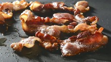 Closeup Of Bacon Strips Frying On A Grill
