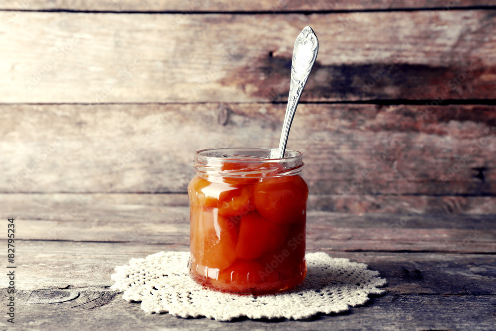Jar of tasty jam on wooden background