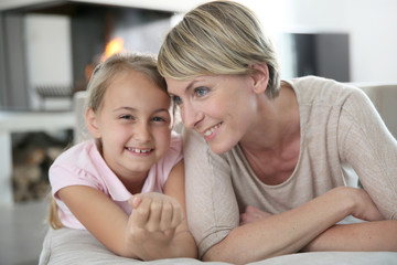 Wall Mural - Portrait of mother and daughter laying in couch at home