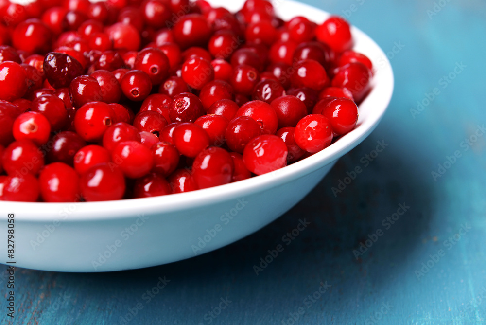 Cranberries in bowl on wooden background