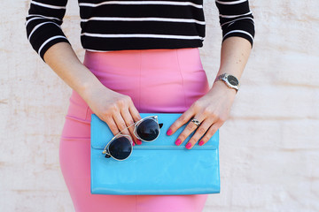 Fashion woman in pink skirt stylish with blue clutch in hand