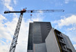 Construction concept: a corporate building with a crane beside.