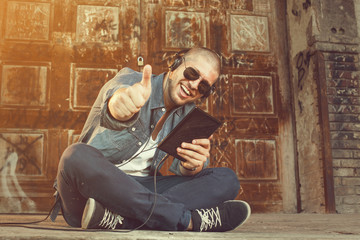 handsome young man listening to music with headphones via tablet