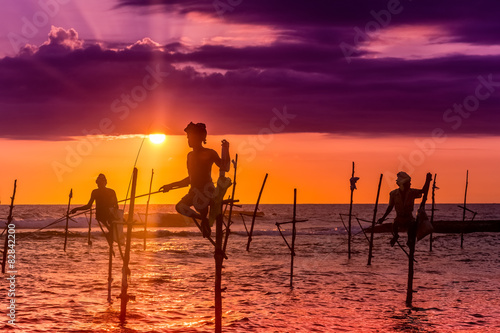Fotografia, Obraz Silhouettes of the traditional fishermen at the sunset near Galle in Sri Lanka