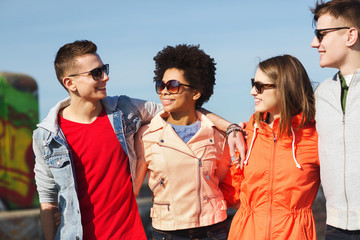 Wall Mural - happy teenage friends in shades talking on street