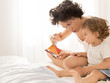 Woman and baby girl reading on bed