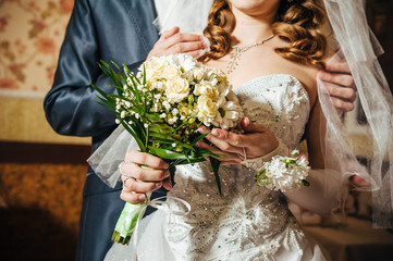 Wall Mural - Hands with wedding rings on bridal bouquet of flowers