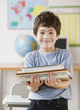 © JGI/Blend Images - Hispanic boy holding stack of school books