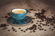 Cup of coffee and coffee beans on burlap background. Toned