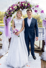 Just Married Couple Standing Under Floral Gates At Wedding Cerem