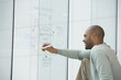 © Klaus Tiedge/Blend Images - African businessman writing on clear dry erase board