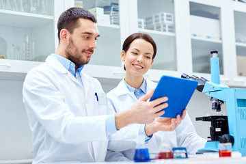 Poster - scientists with tablet pc and microscope in lab