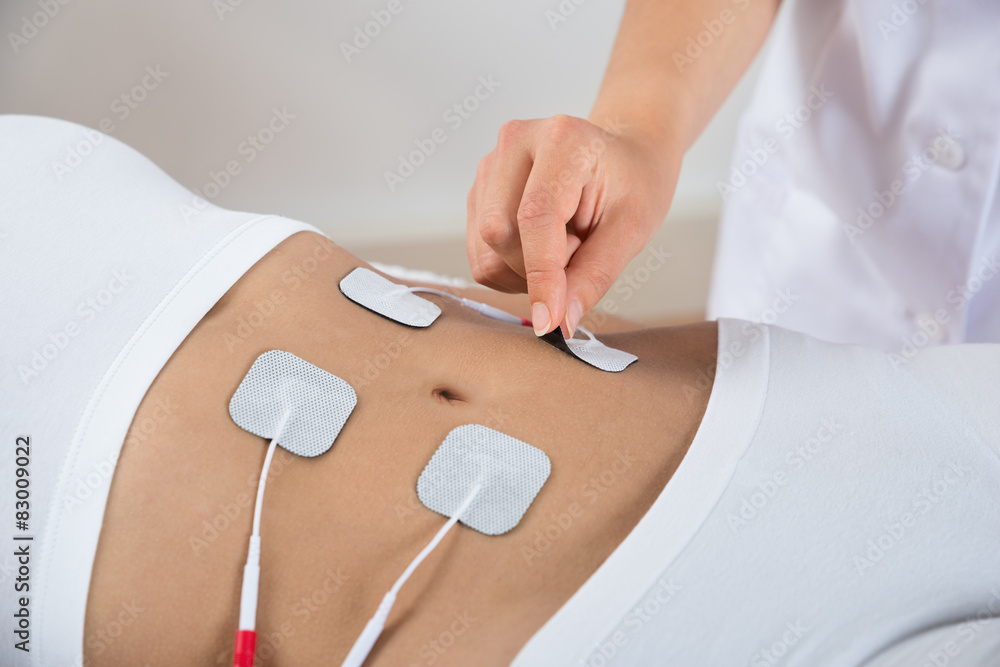 Therapist Placing Electrodes On Woman's Stomach - obrazy, fototapety, plakaty 