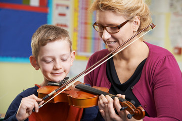 teacher helping pupil to play violin in music lesson