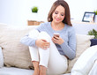 © shefkate - Pretty girl using her smartphone on  couch at home in the living