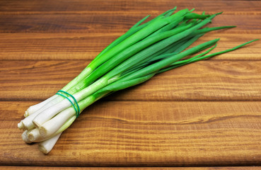 Bunch of fresh green onions laying on a wooden table. Fresh gree