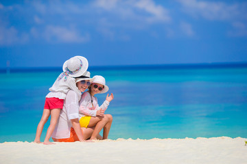 Sticker - Adorable little girls and young mother on tropical white beach 