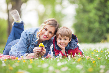 Wall Mural - Smiling young woman having a picnic with her cute little son