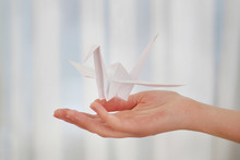 Female Hand With Paper Crane On Blurred Background