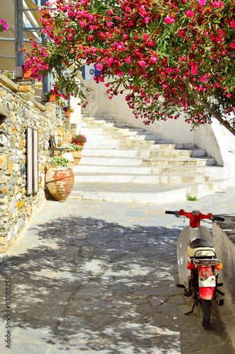 piekna-srodziemnomorska-uliczka-z-czerwonymi-kwiatami-i-retro-skuterem-wyspa-naksos-grecja