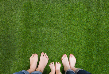 Family legs standing together on green grass