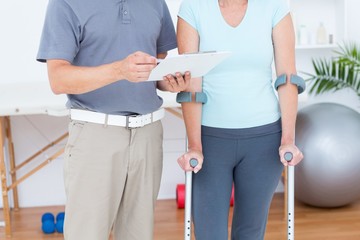 Wall Mural - Woman using crutch and talking with her doctor