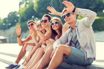Wall Mural - group of smiling friends sitting on city street