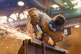 Fototapeta  - Young man with protective goggles welding in a factory