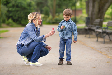 Wall Mural - Cute little boy playing with his mother outdoors 