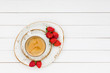Cup of coffee and strawberries on white wooden table. Top view