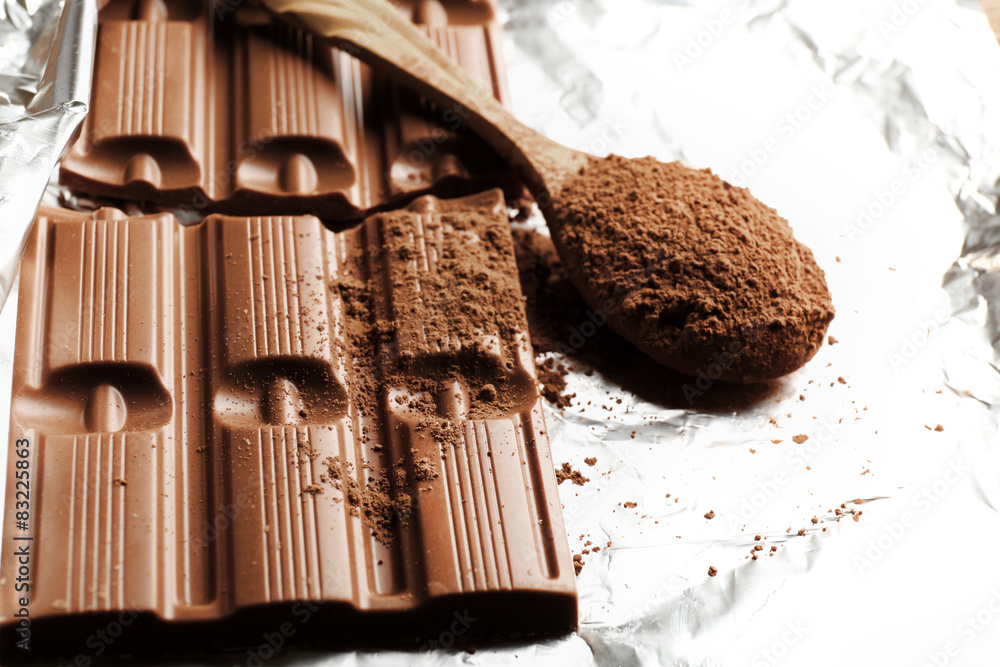 Bar of chocolate with cocoa on foil, closeup