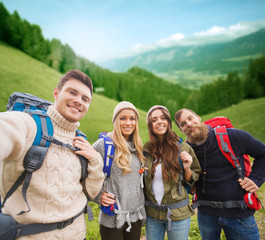 Canvas Print - group of smiling friends with backpacks hiking