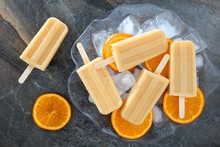 Homemade Orange Yogurt Popsicles In An Ice Filled Bowl