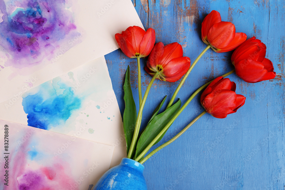 Red tulips in vase on wooden background top view
