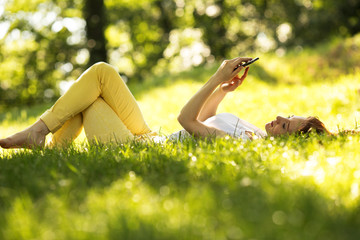 Woman  using a smart phone  at the park.Doing selfie.