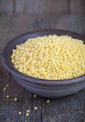 Wall Mural - Dry Israeli couscous ptitim in a clay bowl on wooden table